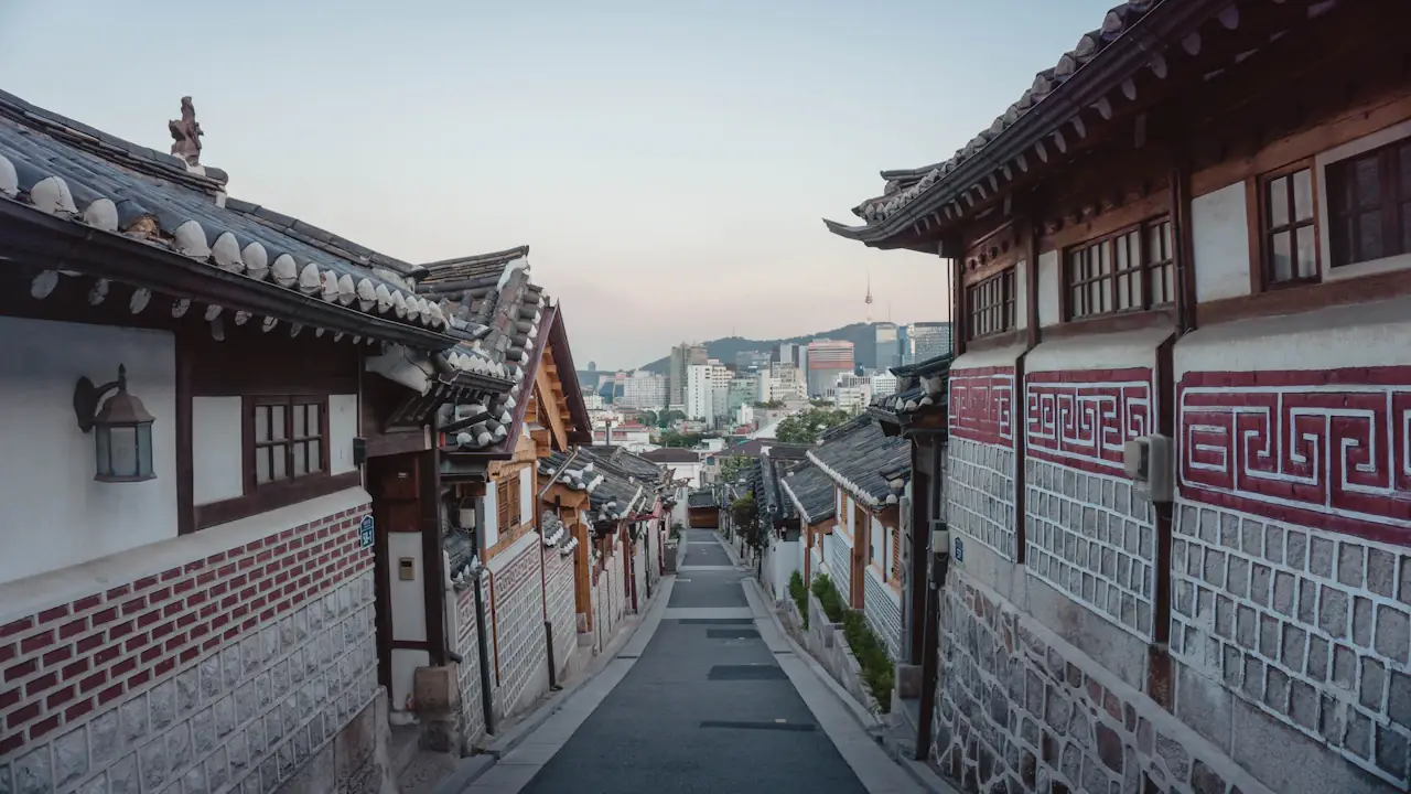 A traditional hanok alley in Seoul with the city skyline in the distance