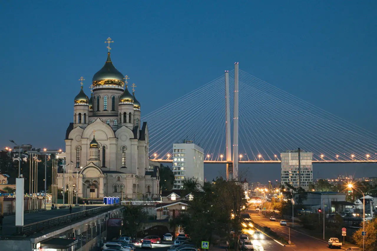 Vladivostok at dusk, the cable-stayed Golden Bridge behind an Orthodox church