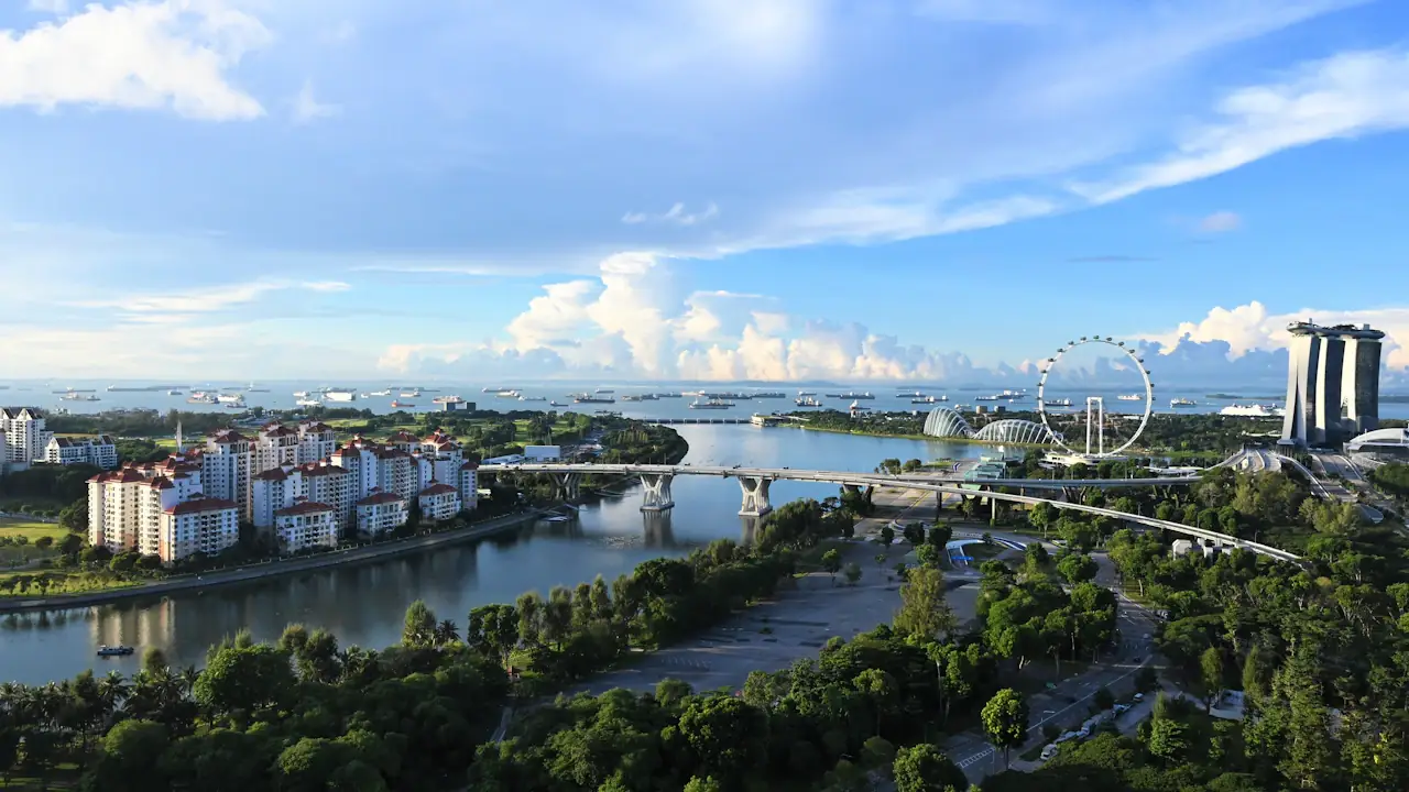Aerial view of Singapore: a river, towers and a distant observation wheel under a partly cloudy sky