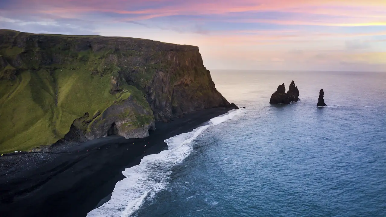 Reynisfjara black sand beach near Vik, Iceland: green cliffs and sea stacks