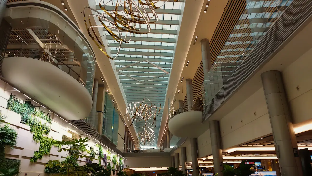 Atrium inside Singapore Changi Airport: glass skylight, hanging art installation and planted walls either side