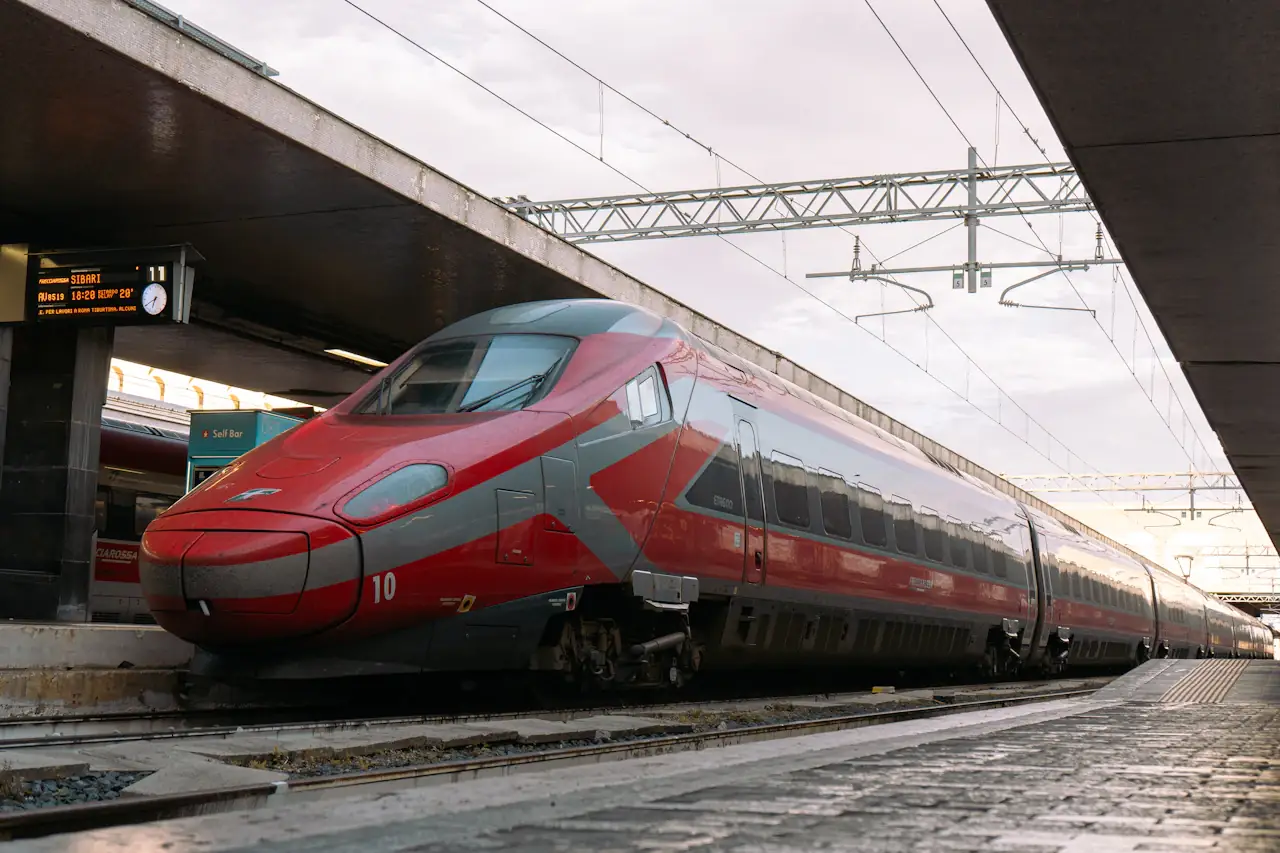 A red-and-grey high-speed train standing at a platform in Roma Termini station