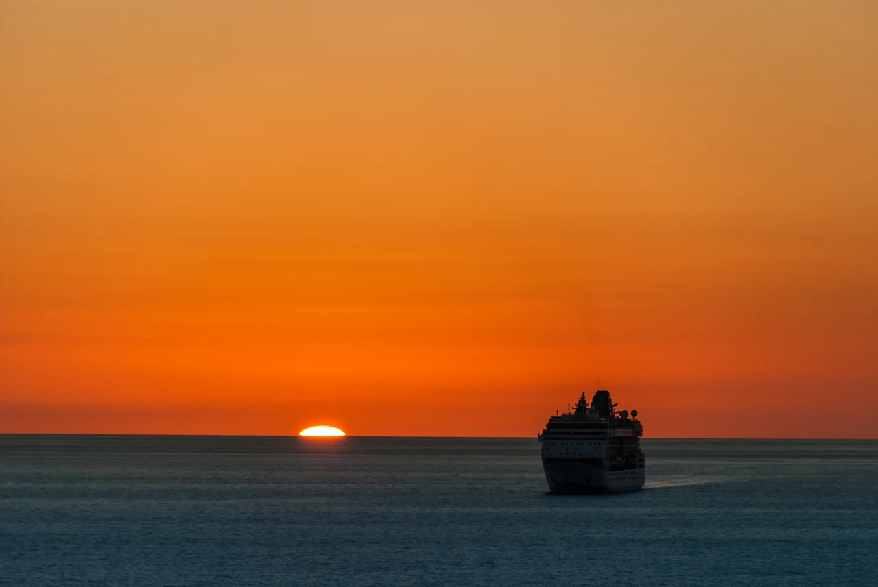 夕阳沉入海面，远处一艘邮轮划过