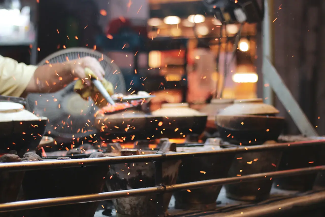 Sparks flying as a cook works clay-pot stoves at night in Kuala Lumpur Chinatown