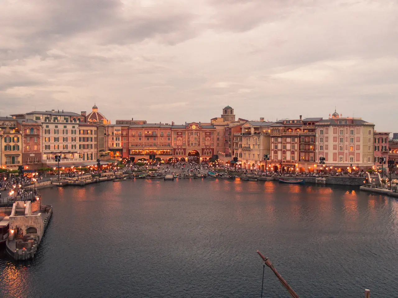 Mediterranean Harbor at Tokyo DisneySea at dusk: Italian-style buildings with arcades across calm water