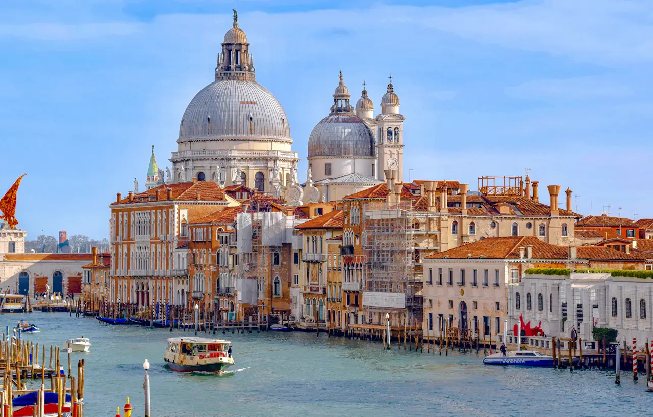 The Grand Canal in Venice with terracotta palazzi on both banks, the white domes of Santa Maria della Salute beyond and a vaporetto on the water