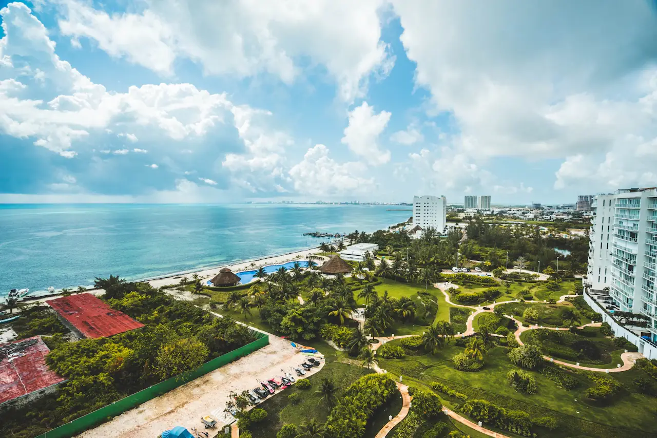 Aerial view of Cancún's hotel-zone coast: green grounds, hotel blocks and the sea beyond