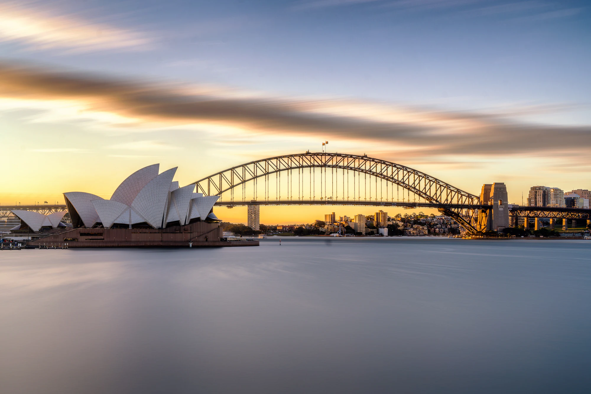Sydney Opera House and Harbour Bridge at dusk, the water softened by a long exposure