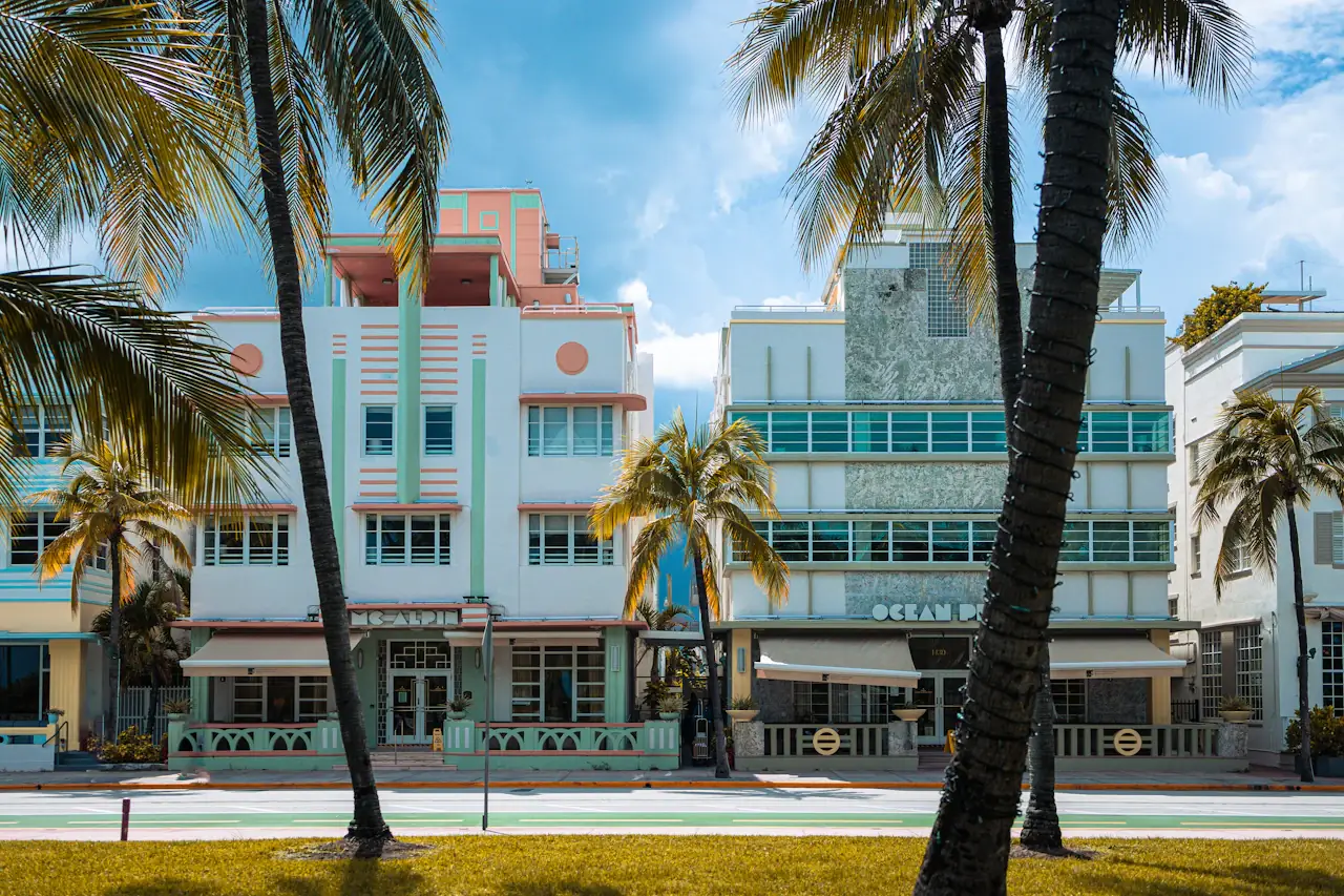 Pale Art Deco hotel buildings on Ocean Drive in Miami Beach, palm trees in front and a blue sky