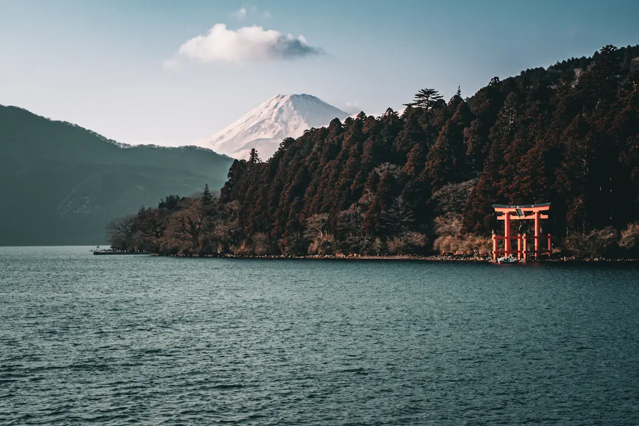 A red torii on a lake shore with Mount Fuji beyond